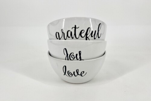 Stack of white bowls with black cursive words reading 'grateful', 'you', and 'love'.