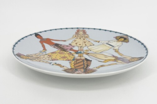 Decorative porcelain plate with a circular illustration of people in colorful traditional dress dancing in a ring, edged with a stitched blue border.
