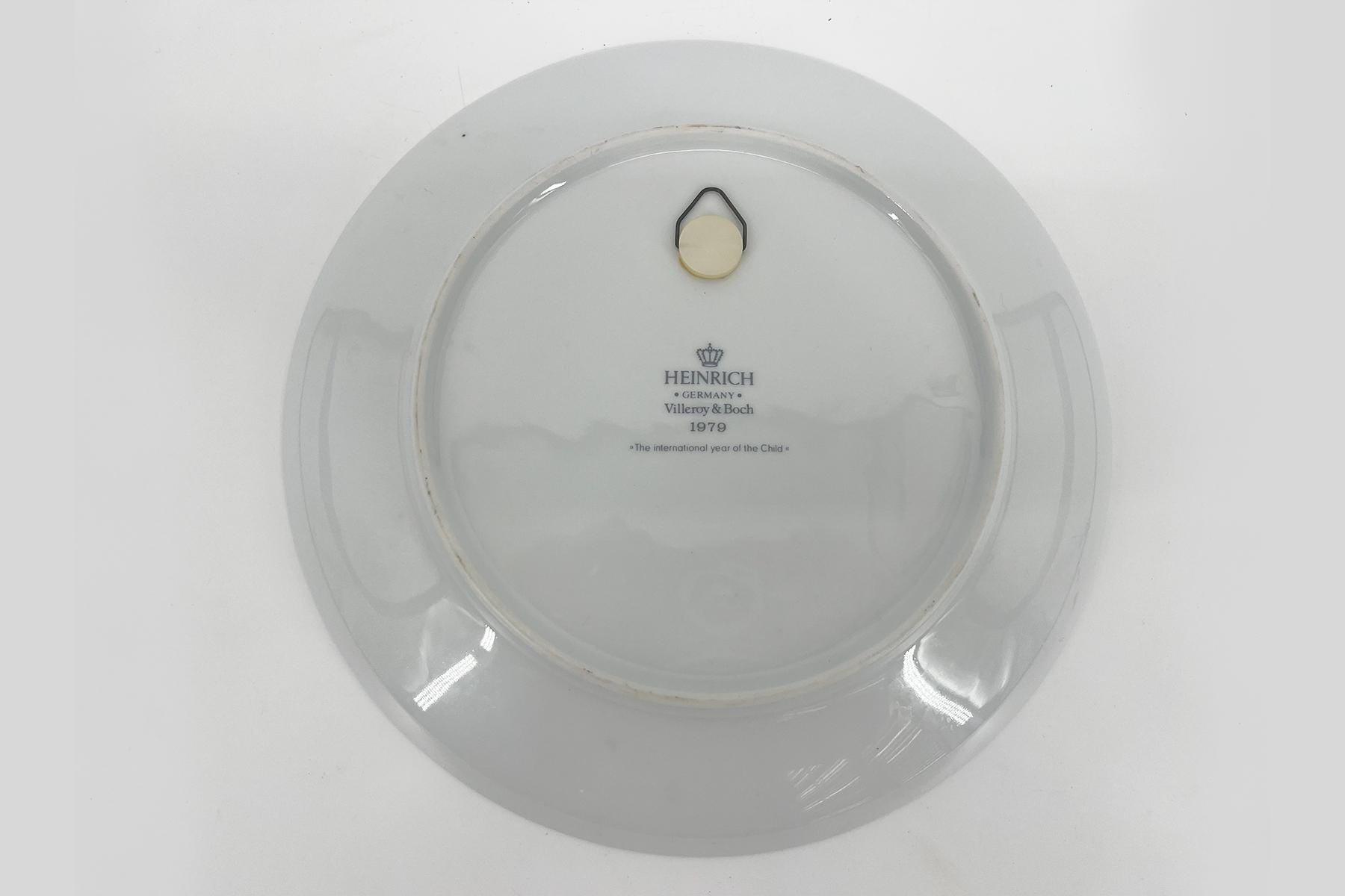 Bottom of a white plate showing a beige stopper and black hanging ring, with HEINRICH GERMANY Villeroy & Boch 1979 stamp and 'The international year of the Child' text