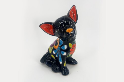 Colorful ceramic dog statue with a black glaze and bright multicolored floral patterns, red inside the ears, and orange nose.