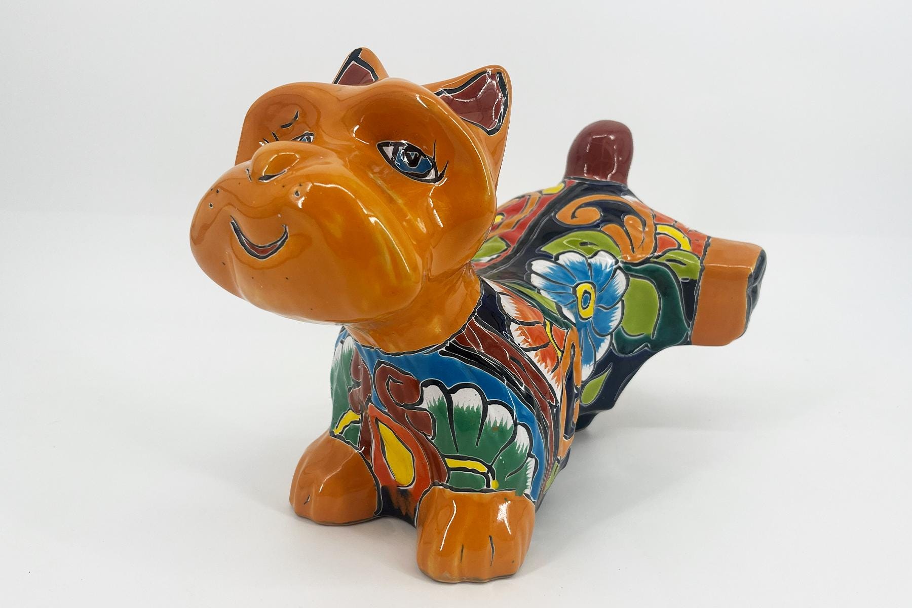 Colorful ceramic bulldog statue with floral patterns and orange glaze, viewed from the front-left corner on a white background.