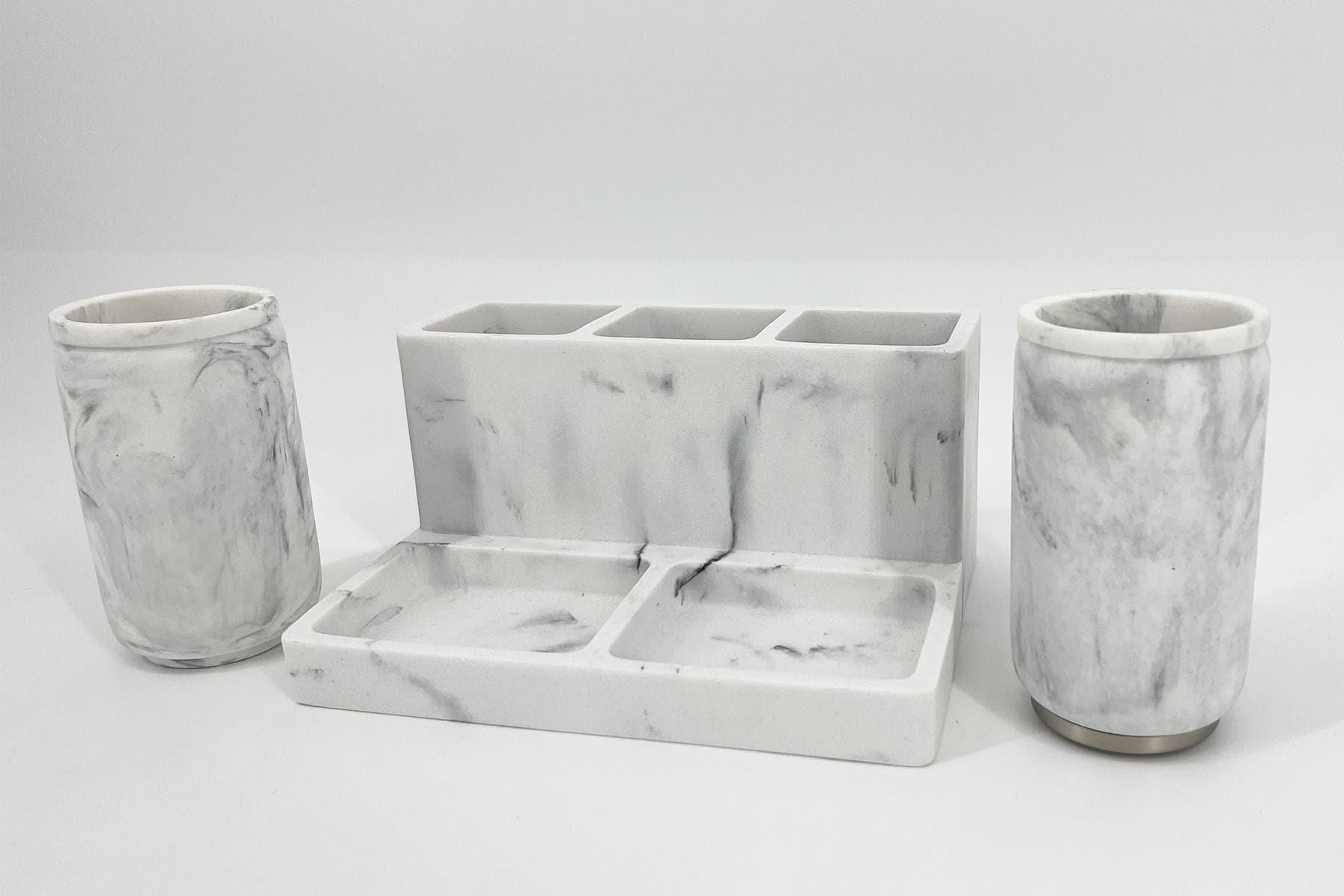 White marble bathroom set: a central three-slot organizer flanked by two marble cylindrical containers.