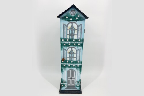Tall decorative house sculpture with blue walls, white window shutters, and a front door mounted on a black base.