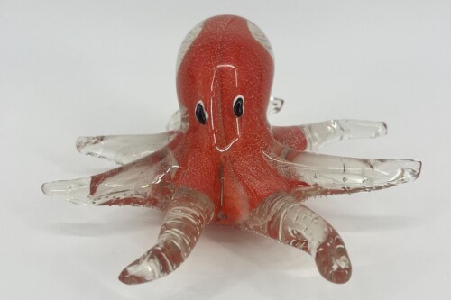 Glass octopus figurine with a red body and transparent tentacles, smiling cartoon face on head