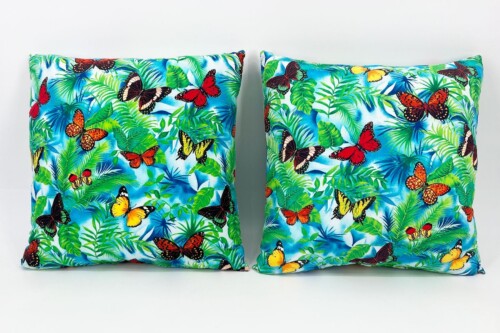 Two decorative pillows with a tropical butterfly and foliage pattern on a bright blue background.