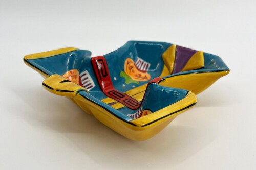 Decorative ceramic boat sculpture with a yellow hull and blue interior, featuring red straps and colorful geometric patterns inside.