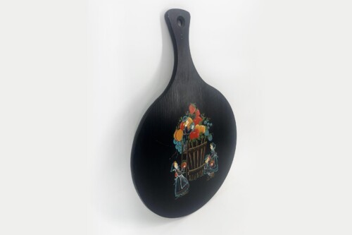 Black wooden cutting paddle with a hanging hole at the top and a colorful fruit-harvest scene painted on the blade.
