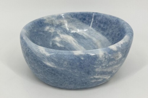 Blue marble bowl with white veining, shown from the side on a white surface, highlighting its curved rim and polished finish.