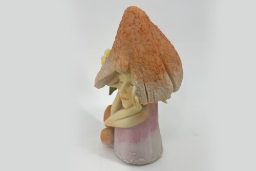 Ceramic figurine of a girl with a large orange mushroom-cap hat, resting her chin on her hand.