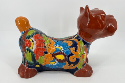 Ceramic statue of a dog with a glossy red head and a multicolored floral glaze along its body.