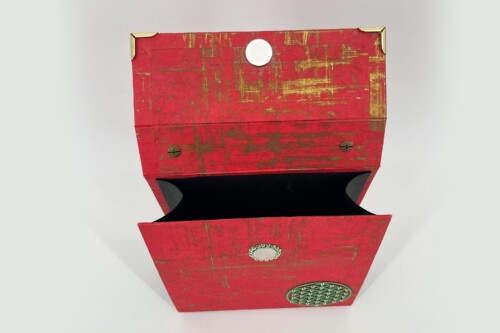 Red distressed wooden box stack with gold trim, opened to reveal a black interior and decorative metal medallions on the front.
