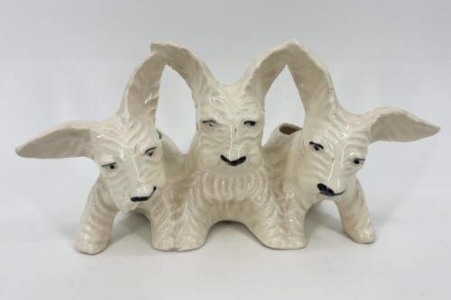 White ceramic sculpture featuring three goats linked together, each with long curved horns and subtle facial details.