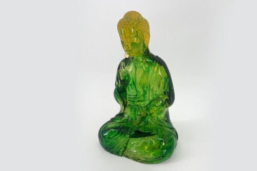 Green glass Buddha statue in a meditative pose, hands resting on lap, tranquil and translucent.