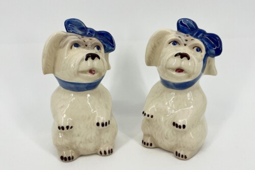Two ceramic bulldog figurines with blue bows and collars facing each other.