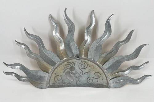 Metal sunburst sculpture with wavy silver rays radiating from a central circular disk featuring abstract motifs in a galvanized finish.