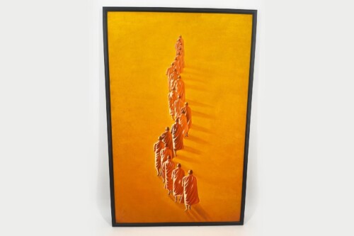 Framed orange-toned photograph of Buddhist monks walking in a single-file line across a bright orange background
