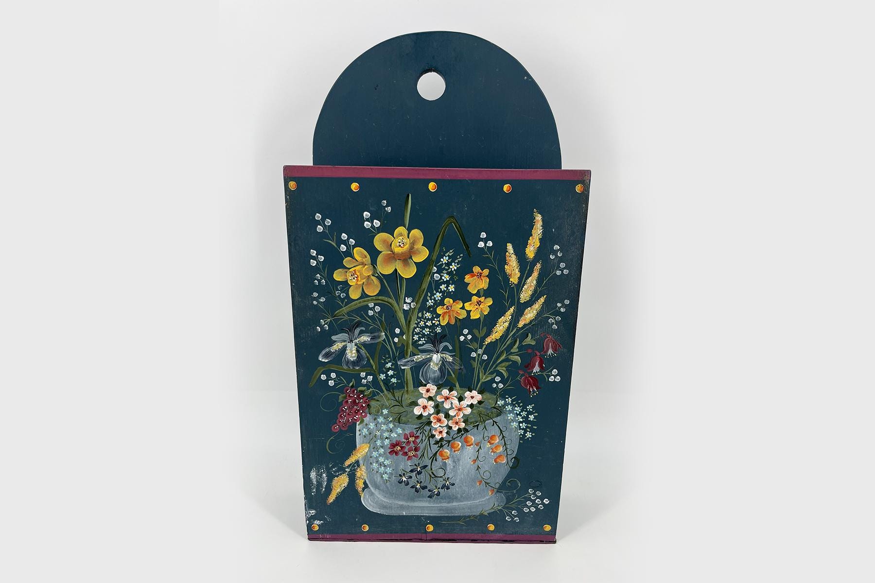 Decorative blue wooden panel with a painted bouquet of yellow and white flowers in a vase.
