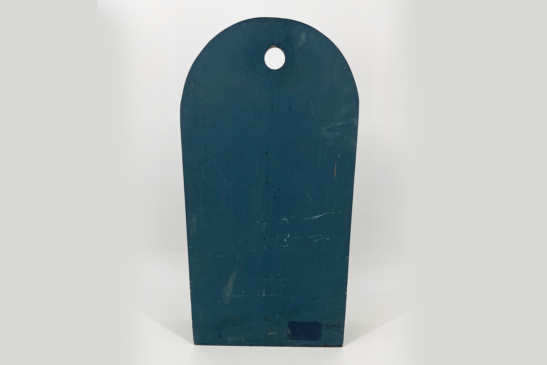Blue wooden cutting board with a rounded top and a hanging hole at the center top.