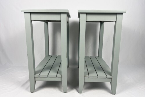 Two identical light gray wooden stools (or small tables) with slatted lower shelves standing side by side.