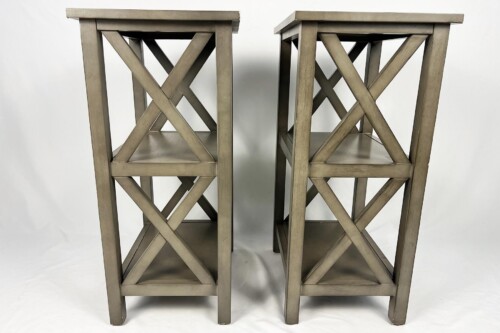 Two gray metal stools with crisscross X-brace legs, standing side by side against a neutral backdrop.
