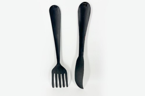 Three black plastic kitchen utensils: left a long-handled spatula, middle a slotted fork, right a curved-edged spatula.