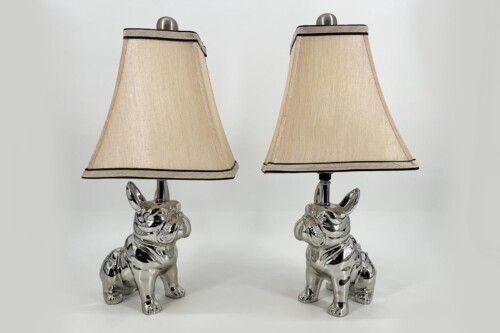 Pair of silver bulldog-shaped table lamps with beige fabric shades and black trim on top and bottom edges.
