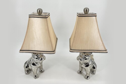Pair of chrome dog-shaped lamp bases supporting beige fabric lampshades with black trim