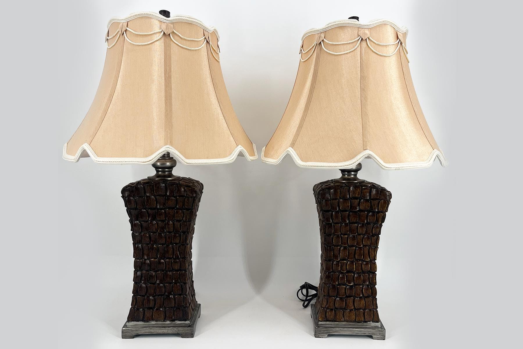 Two matching table lamps with cream-beige scalloped lampshades and dark textured bases.