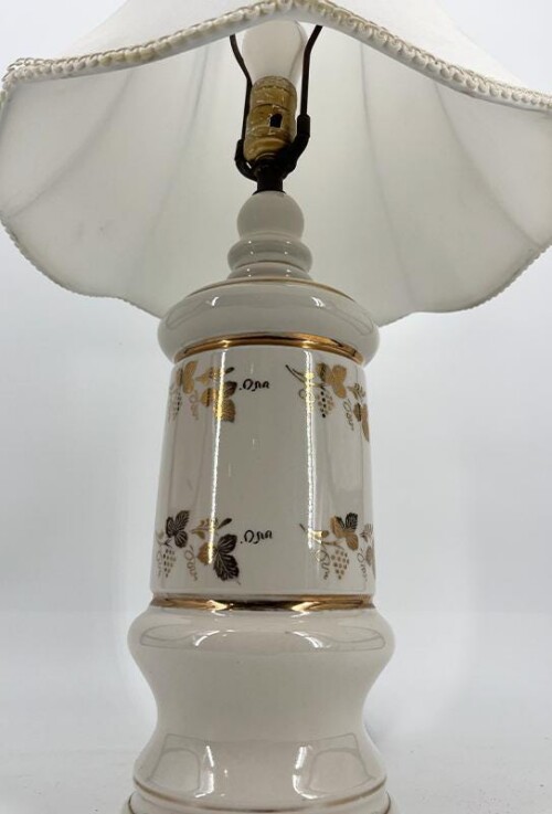 White ceramic table lamp with a gold butterfly pattern and a white fabric lampshade; bulb socket visible at the top.