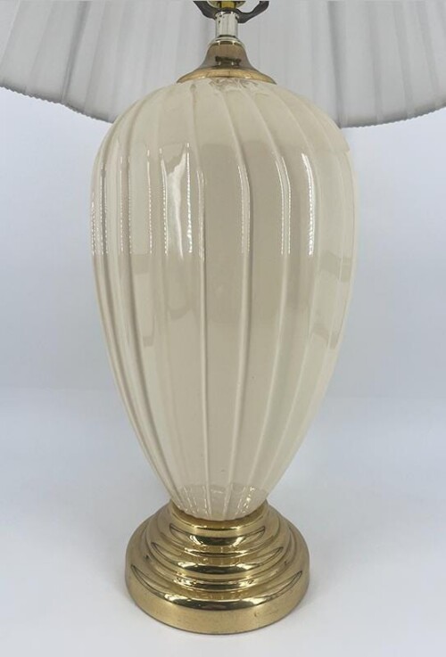 Table lamp with a ribbed white glass body and a brass base to sit on a surface.