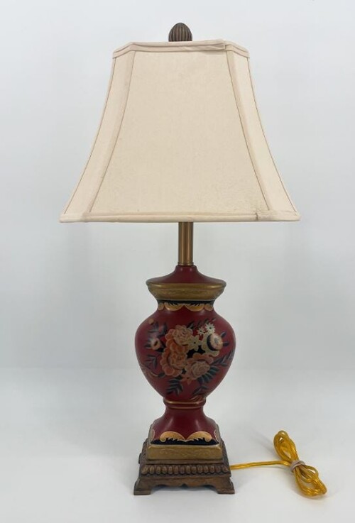 Decorative table lamp with a red floral ceramic base, brass stem, and a cream lampshade on a white background.