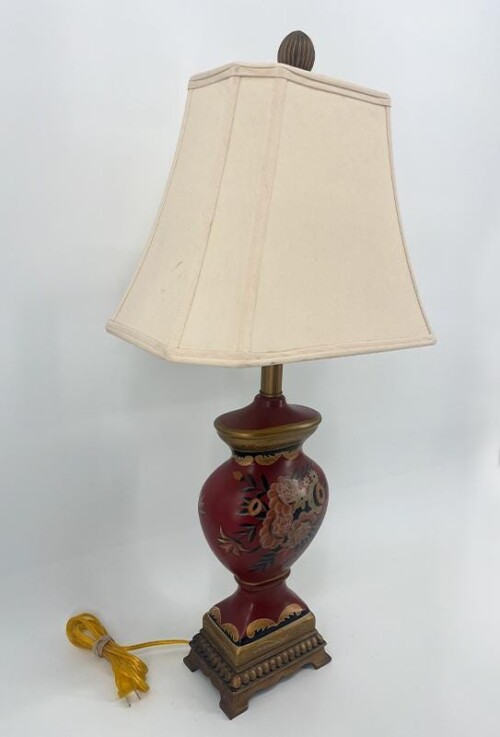Decorative table lamp with a red floral ceramic base, ivory fabric shade, and a yellow cord.