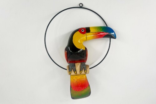 Colorful wooden toucan sculpture hanging by a circular metal ring, a decorative ornament with a rainbow beak and bright colors