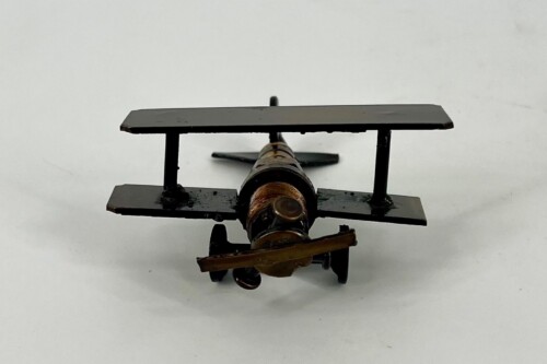 Front view of a small vintage model biplane with black wings and brown fuselage on a white background.