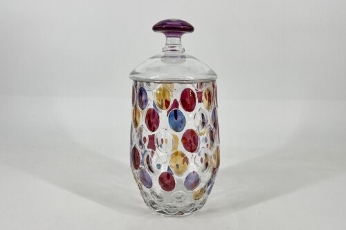 Clear glass storage jar with a purple knob lid and colorful circular accents around its body, decorative storage piece