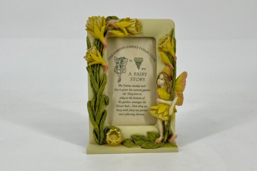 Decorative garden fairy sculpture and plaque titled 'A Fairy Story' framed with yellow flowers and a small fairy figure on the right