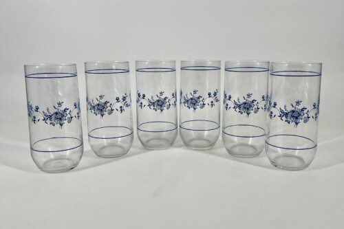 Six clear tall drinking glasses arranged in a row, each with a blue floral band and rim detailing.