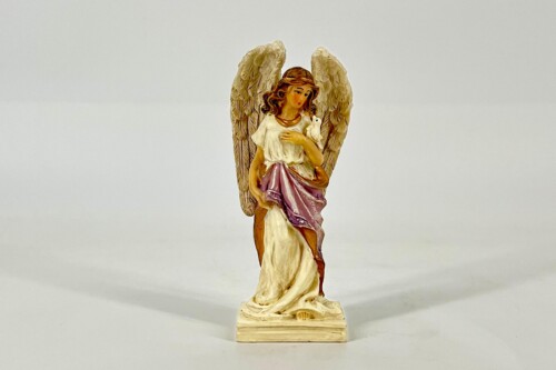 Statue of an angel with large wings, wearing white and purple robes, holding a white dove against a pale background.