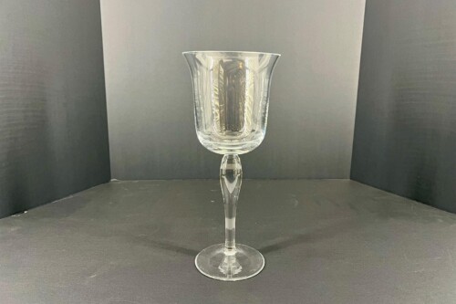 Clear crystal goblet with a flared bowl and faceted stem, centered on a dark backdrop.