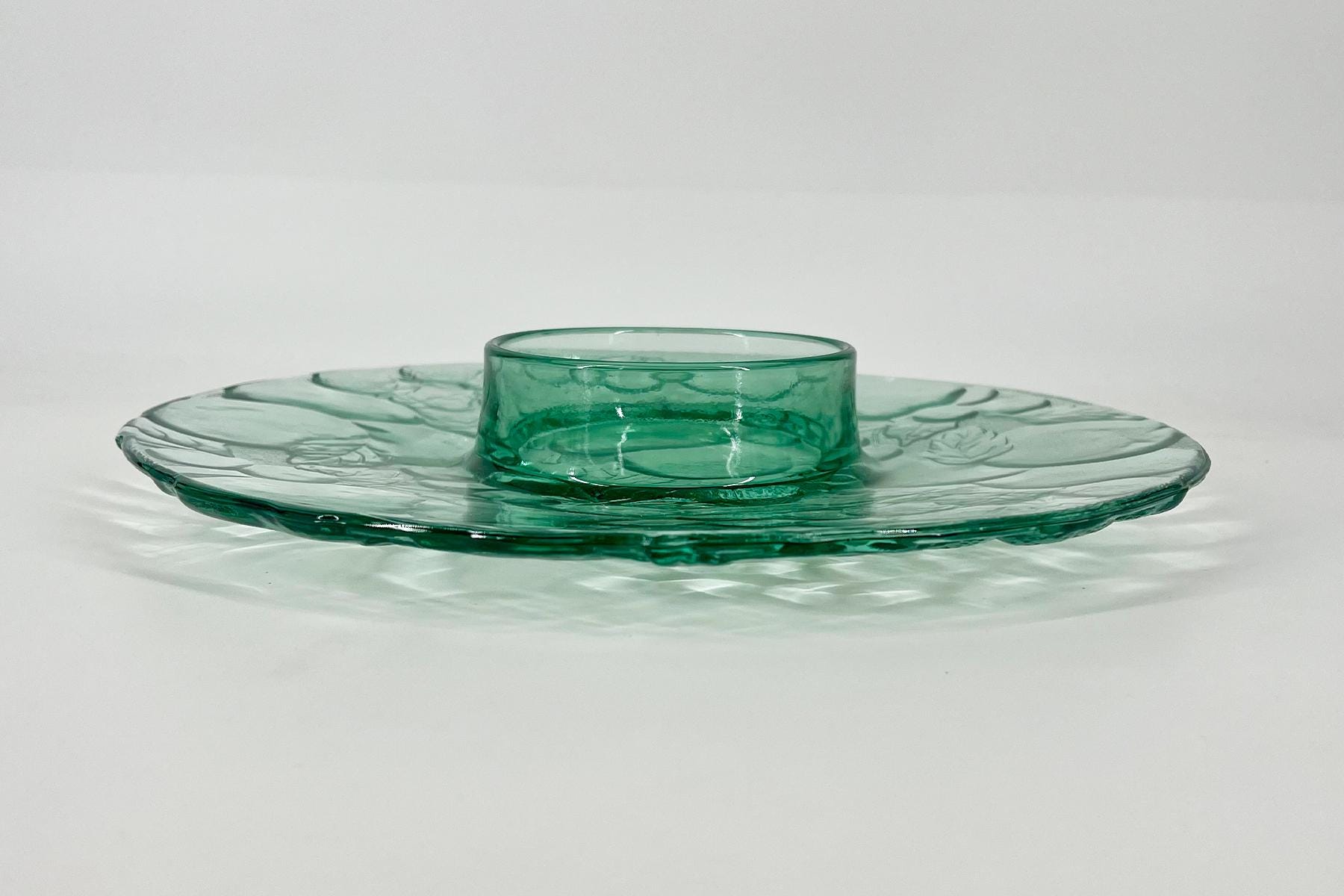 Teal glass plate with a raised central ring, set on a light background.