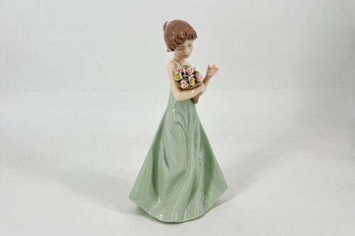 Porcelain figurine of a girl in a mint-green dress holding a bouquet of pink and yellow flowers, looking down gracefully.