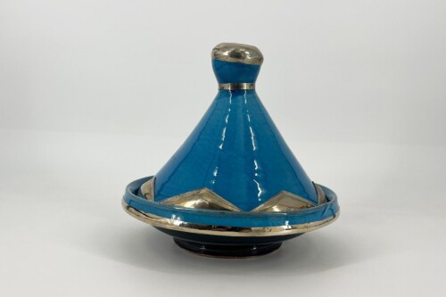 Glossy blue spinning top with silver trim and cap on a white surface.