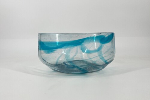 Glass bowl with swirling blue liquid inside, photographed against a white background.