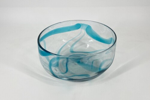 Clear glass bowl with turquoise-blue swirl patterns inside, photographed against a white background, viewed from above