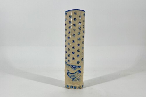 Tall beige ceramic vase with blue dotted holes and a blue fish motif near the bottom edge