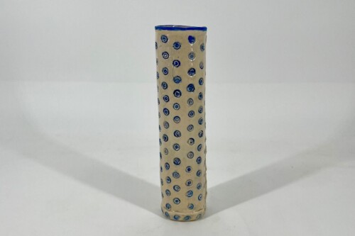 Tall beige ceramic vase with blue circular dot pattern on a white surface, centered in the frame.