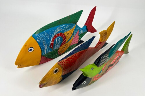 Colorful painted wooden fish sculptures with floral patterns and bright fins arranged in a row on a white background.