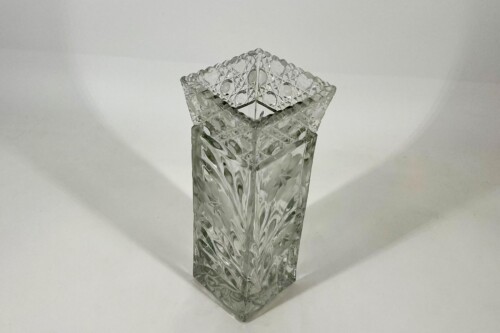 Crystal cut-glass square vase with an ornate faceted rim, empty on a white surface.