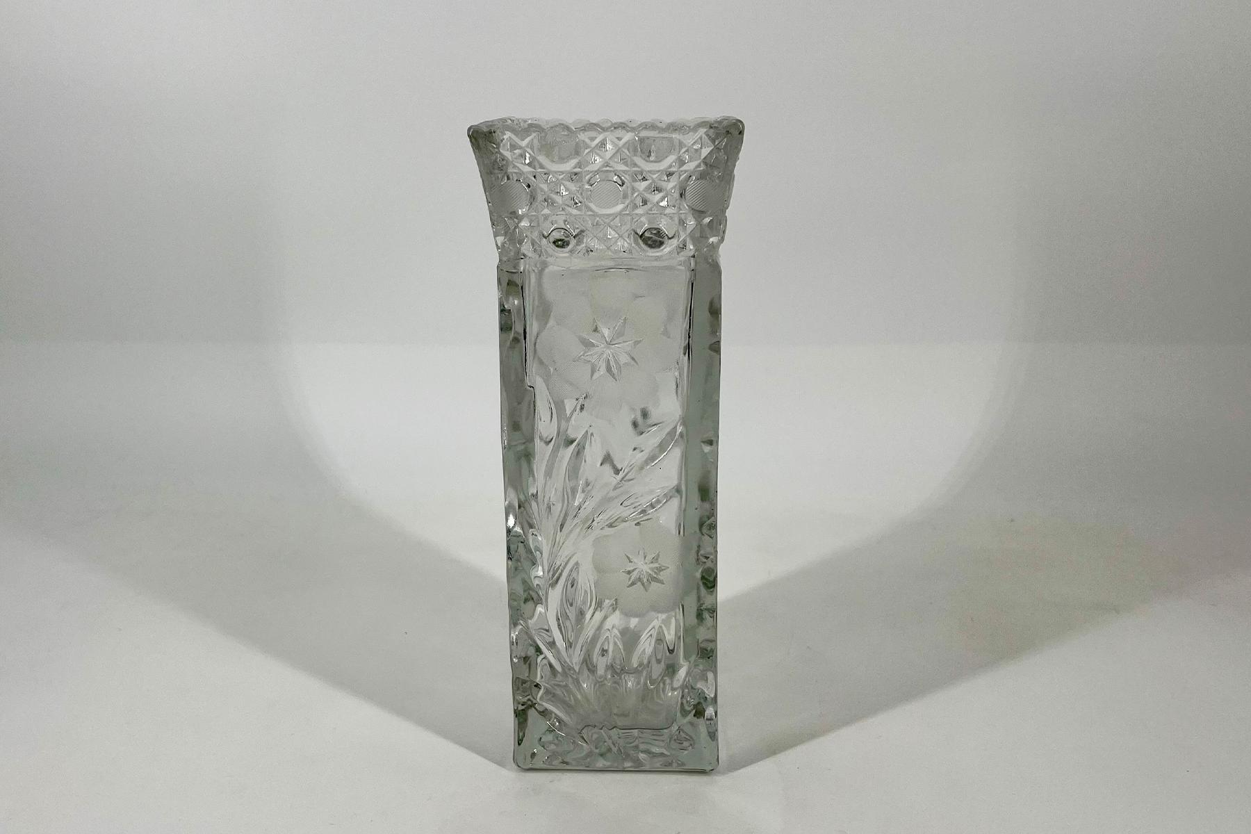 Tall clear cut-glass vase with starburst etchings, standing on a white surface.