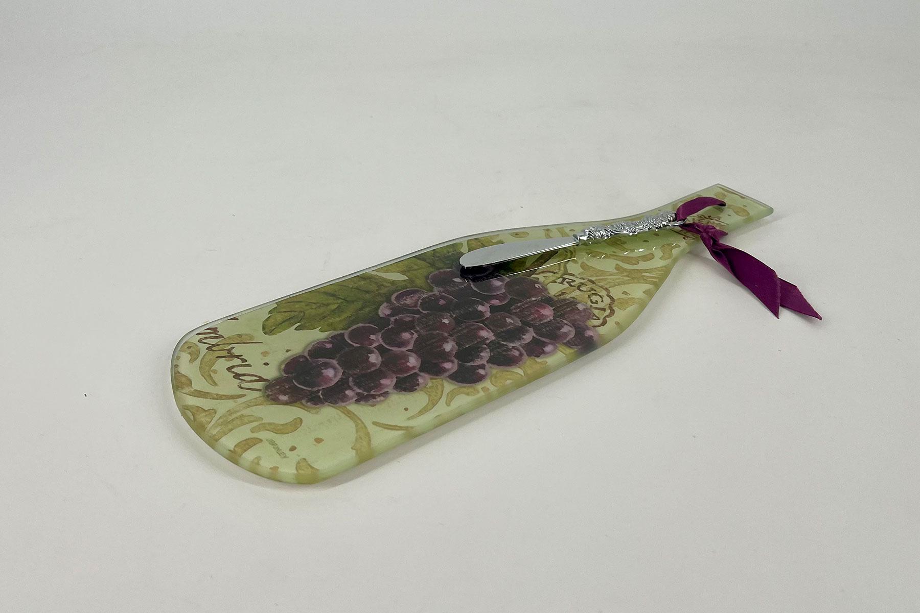 Decorative cake server with a grapevine pattern on the blade and a purple ribbon tied at the handle